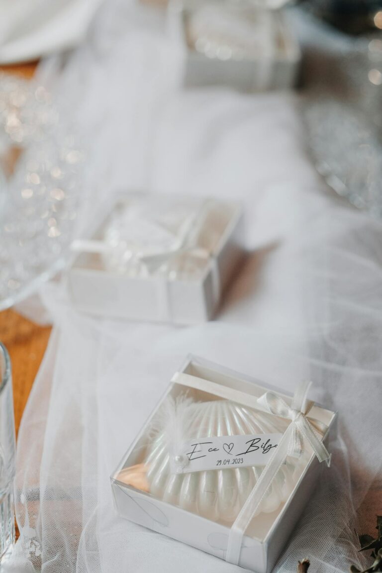 Delicate white gift boxes with personalized wedding tags on elegant fabric.